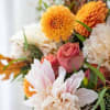 Bouquet of orange dahlias, pink roses, and pale white flowers