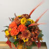 Orange roses and yellow mums in a fall bouquet with ribbon and decorative leaves