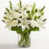 White lilies and roses arranged in a clear glass vase