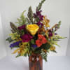 Mixed bouquet of roses and fall flowers in an amber glass vase