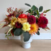 Colorful mixed bouquet in a white vase with dahlias and greenery
