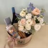 Flower arrangement in a round gift box with wine and tea tins