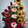 Tall arrangement of red roses, yellow sunflowers, pink gerbera daisies, and pink lilies