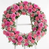 Pink floral wreath with roses and carnations on a white stand