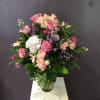 Pink roses and mixed flowers arranged in a clear glass vase