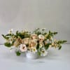 Low floral arrangement of blush roses and white daisies in a white vase