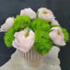 Pale pink flowers arranged in a ribbed white vase with bright green filler