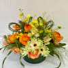 Orange and white mixed flower arrangement in a low green vase