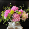 Pink and pale yellow flowers arranged in a silver vase