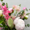 Pink and white flowers arranged with greenery in a bouquet