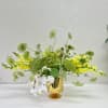 Green and white floral arrangement in a gold speckled vase