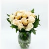 White roses with gold-wrapped chocolates in a glass vase