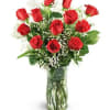 Red roses arranged in a clear glass vase with baby's breath
