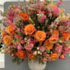 Large wedding arrangement of orange and pink roses in a white vase