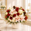 Red roses and pale lilies in a white vase with pinecones and berries