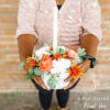 White pumpkin centerpiece with orange and white flowers and a candle