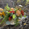 Mixed bouquet in a woven vase with peach, red, and white flowers