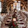 Long banquet table with red rose centerpieces and candles in a decorated hall