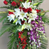 Tall standing floral spray with red roses, white lilies, and purple orchids