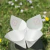 Four white paper cone holders with pink monogram marks on a dark base