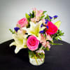 Bouquet of pink roses, white lilies, and pink alstroemeria in a glass vase