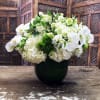 White floral arrangement in a dark vase with orchids and hydrangeas