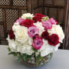 Bouquet of red, pink, and white roses in a glass bowl vase