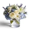 White roses and lilies with blue hydrangeas in a glass vase
