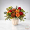 Orange and red flowers arranged in a cream vase