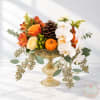 Autumn floral arrangement in a gold pedestal vase with white orchids and orange roses