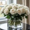White roses arranged in a clear square glass vase