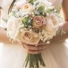 Bride holding a bouquet of blush and white roses with baby's breath