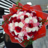 Large bouquet of red, pink, and white roses wrapped in red paper