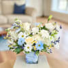 White and blue mixed bouquet in a square glass vase