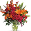 Bright bouquet of roses and orange lilies in a clear glass vase