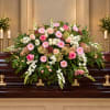Large pink and white floral spray on a dark casket