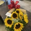 Bouquet of sunflowers wrapped in brown paper with a red ribbon bow