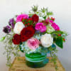 Bouquet of red, pink, and white roses in a green glass vase