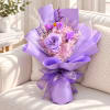 Lavender and pink bouquet wrapped in purple paper on a sofa