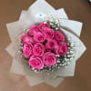 Bouquet of bright pink roses with white baby's breath in white wrap