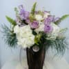 Lavender roses and white hydrangeas in a tall vase with fern accents