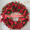 Heart-shaped red floral sympathy wreath with ribbon on an easel