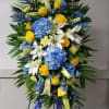 Tall blue, yellow, and white funeral spray on a stand