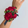 Red rose wrist corsage with green leaves and a black ribbon