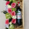 Pink and white roses arranged beside a wine bottle in a wooden gift box