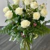 Bouquet of white roses in a clear glass vase with mixed greenery