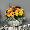 Yellow and burgundy floral arrangement in a silver pumpkin container