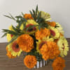 Bouquet of yellow gerbera daisies and orange marigolds in a white vase