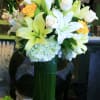 Bouquet of white lilies, white roses, and yellow roses in a tall green vase