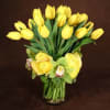 Yellow tulips and roses arranged in a clear glass vase